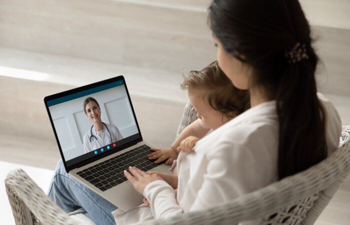 Loving young mother holding baby, making video call to pediatrician